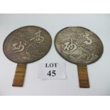 A pair of Chinese white metal polished hand mirrors decorated to reverse with embossed scene