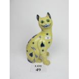 A large Galle style yellow ground model pottery cat with glass eyes and blue painted decoration