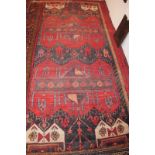 A fine Baluchi carpet on red ground (310 x 152 cm approx) est: £150-£250