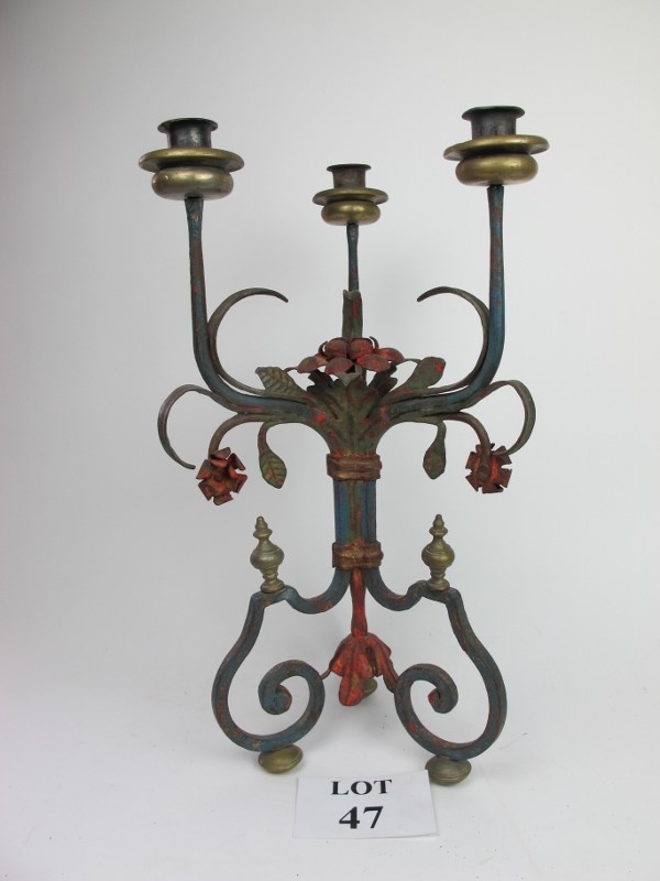 A large, painted cast iron three branch candelabra with rose motifs and decoration,