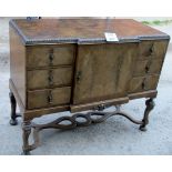 An early 20c walnut sideboard with a centre cupboard flanked either side by drawers over an ornate