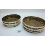 A pair of silver coasters with scroll de