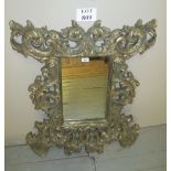 An elaborately painted and carved wall mirror with silvered finish est: £40-£60