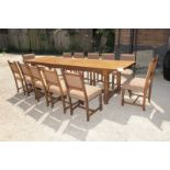 An Edwardian solid oak 10ft long refectory dining table and a set of twelve oak dining chairs all