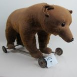 An early 20th century child's bear on wheels, possibly Bing, straw filled, metal frame,