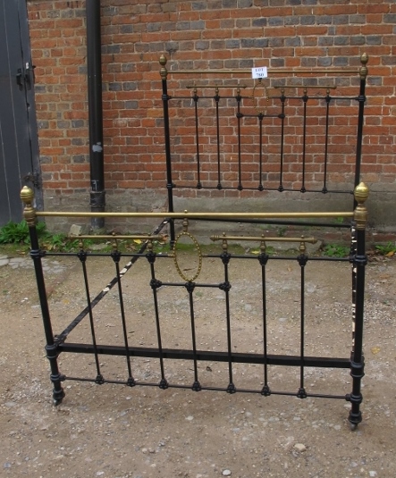 A Victorian wrought iron black bed frame with highlights,