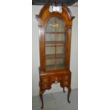 A 20th century mahogany Queen Anne design two section cabinet of arched form with a glazed door to