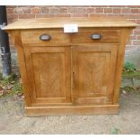 A 19th century pine cabinet with two drawers over panelled cupboard doors with carved floral