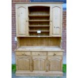 A 20th century pine dresser with five shelves to top flanked either side by cupboards over three
