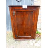 A 19th century oak corner cupboard with panelled door revealing two fixed,