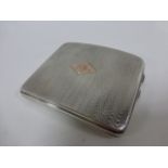 A silver cigarette case with engine turned decoration and 9ct gold cartouche,