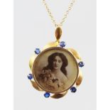 A GOLD COLOURED METAL LOCKET PENDANT, bordered with six sapphires interspersed with plain stylised