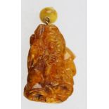 AN AMBER PENDANT carved with an Oriental figure holding a vase, 4.25" high