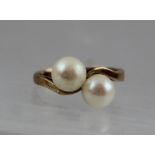 A PEARL CROSSOVER STYLE GOLD DRESS RING, having two pearls, size G 1/2