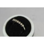 A RHODIUM FINISHED WHITE GOLD HALF HOOP ETERNITY RING, set with seven diamonds in claw setting, on a