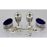 STOKES & IRELAND LTD. A PAIR OF REGENCY DESIGN SILVER SALTS, of pierced form with blue glass liners,