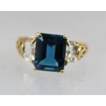 A 9CT GOLD LADY'S DRESS RING, set with a rectangular cut blue stone, flanked by clear stones to