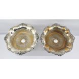 A PAIR OF SILVER PLATED WINE BOTTLE COASTERS, of cast floral design rims and turned wood bases, 20cm