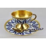 A RUSSIAN SILVER GILT CUP AND SAUCER WITH TEASPOON, wire work cloisonne decoration, in blue on white