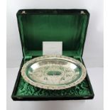 A WHITE METAL PRESENTATION OVAL DISH with pierced decorative rim and leaves to the sole,