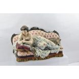 A LATE 19TH CENTURY FRENCH PARIAN FIGURE, a woman reclining on a sofa, with her cat, polychrome