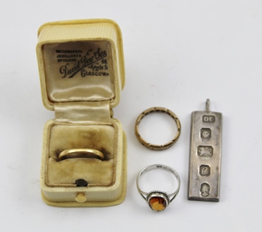 AN 18CT GOLD WEDDING BAND, two costume rings and a silver ingot pendant.