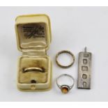 AN 18CT GOLD WEDDING BAND, two costume rings and a silver ingot pendant.