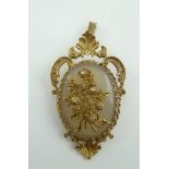 A 9CT GOLD DECORATIVELY FRAMED BROOCH with pendant mount, the polished central cabochon bearing a