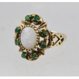 A 9CT GOLD LADY'S DRESS RING inset central oval opal surrounded by emeralds, size N easy