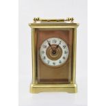 A LATE VICTORIAN BRASS FRAMED CARRIAGE CLOCK inset with bevelled glass panels, the dial with