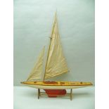 A 20TH CENTURY PAINTED WOOD POND YACHT with fabric sails and stand, 99cm long