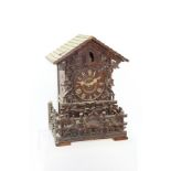 A BLACK FOREST CUCKOO CLOCK of architectural form, with carved fruiting vine decoration to the front