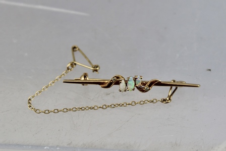 A GOLD BAR BROOCH set three central opals with diamonds, pin mount and safety chain