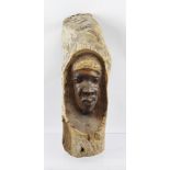 AN AFRICAN HARDWOOD CARVING, a mask emerges within a branch segment, 37cm high