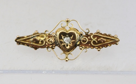 A VICTORIAN GOLD BAR BROOCH set central diamond within a heart and scrolled frame