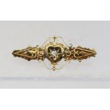 A VICTORIAN GOLD BAR BROOCH set central diamond within a heart and scrolled frame