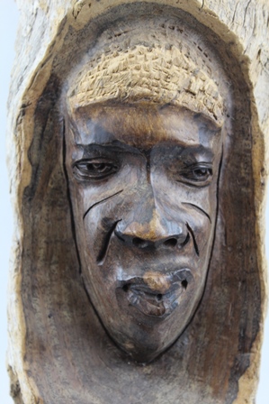 AN AFRICAN HARDWOOD CARVING, a mask emerges within a branch segment, 37cm high - Image 2 of 3