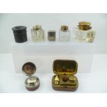 A LEATHER COVERED BRASS TRAVELLING INKWELL with fold-out taper holder, to melt sealing wax, 10cm