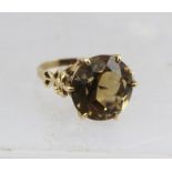 A LARGE TOPAZ 9CT. GOLD RING, having floral design shanks, size P