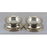 BROADWAY & CO. A PAIR OF SPUN SILVER WEIGHTED BOTTLE/CANDLE STANDS, each having a moulded surround