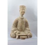A CHINESE POSSIBLY HAN DYNASTY POTTERY "KITCHEN" FIGURE, seated at a low table, 36cm high