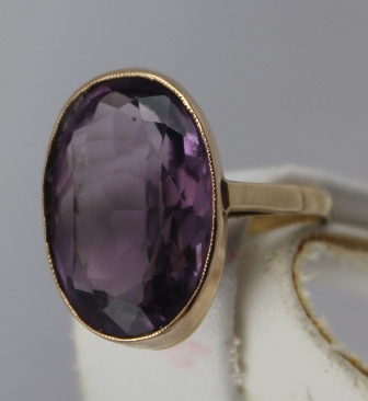 AN AMETHYST SET GOLD DRESS RING, the rub over setting stamped 9ct, set with an oval amethyst, size S