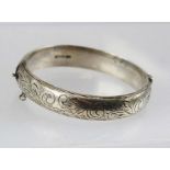 C** P** S** A SILVER BANGLE with engraved front and plain hinged back, snap fit clasp, Birmingham