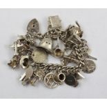 A SILVER CHARM BRACELET, attached numerous charms including; vintage car, grand piano, aladdins