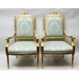 A PAIR OF FRENCH REGENCY DESIGN OPEN ARM FAUTEILS, having carved gilded wood frames with trophy