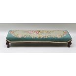 A 19TH CENTURY LONG AND LOW RECTANGULAR FOOTSTOOL with probably later wool work pad top, supported