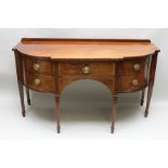 A GEORGE III MAHOGANY BREAKFRONT SIDEBOARD, string inlaid, having a low panel back, fitted drawers