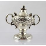 A LATE VICTORIAN WHITE METAL TABLE CIGAR LIGHTER of twin handled urn design with repousse