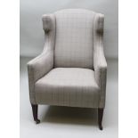 AN EDWARDIAN WING BACK EASY CHAIR upholstered in a neutral check fabric, raised on squared