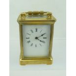 AN EARLY 20TH CENTURY FRENCH BRASS CASED CARRIAGE CLOCK with bevelled glass panels, white enamel